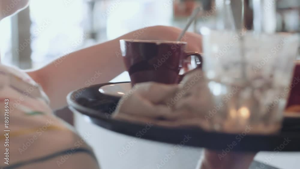 Camera follows female waiter while she carries tray full of dirty plates, cups and cuttlery to bar or kitchen. restaurant and hotel business, busy lunch break or brunch time in hipster cafe