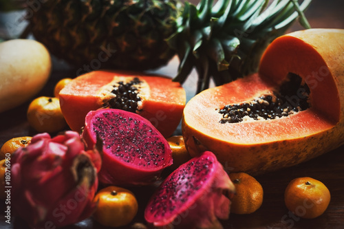 Juicy exotic fruits close up. Pineapple, papaya, mango, gragon fruit on table ready to eat photo