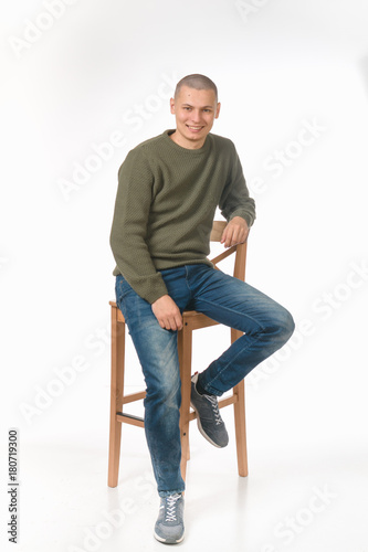 A young man is skinhead in a green military style sweater. studio.