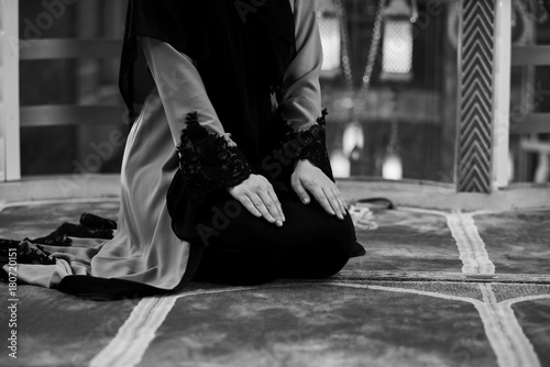 Young pretty muslim woman in hijab praying inside the mosque
