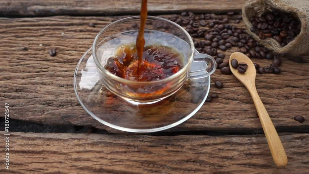 Slow Motion : Pouring hot coffee in to cup on wooden.