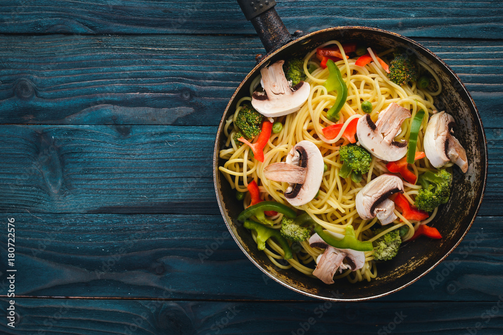 Noodles with vegetables in a frying pan. Asian Cuisine Pasta. Top view. Free space. On a wooden background.; Noodles with vegetables in a frying pan. Asian Cuisine Pasta. Top view. Free space. On a wooden background.;