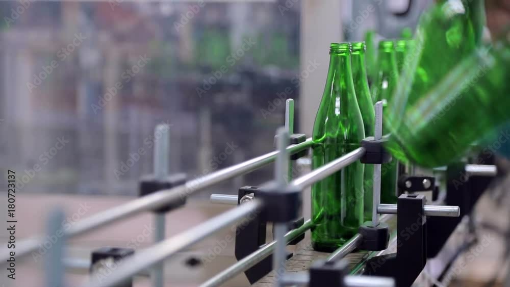 Line of water production. The employee puts the glass bottles on the line of automatic cleaning and filling bottles with water. Breakdown on the line. Bottles are falling. Unregulated technique Line of water production. The employee puts the glass bottles on the line of automatic cleaning and filling bottles with water. Breakdown on the line. Bottles are falling. Unregulated technique