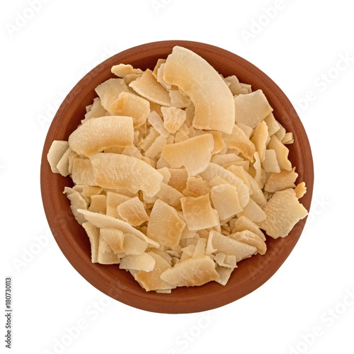 Top view of a small terracotta bowl filled with coconut flakes isolated on a white background.