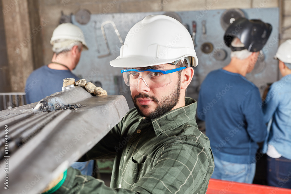 Arbeiter kontrolliert ein Bauteil aus Stahl