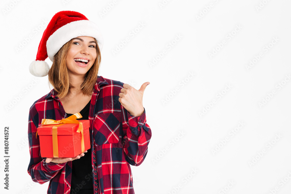 Happy brunette woman in shirt and christmas hat holding gift Happy brunette woman in shirt and christmas hat holding gift