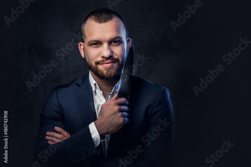 A man in a suit holds a Chef's knife.