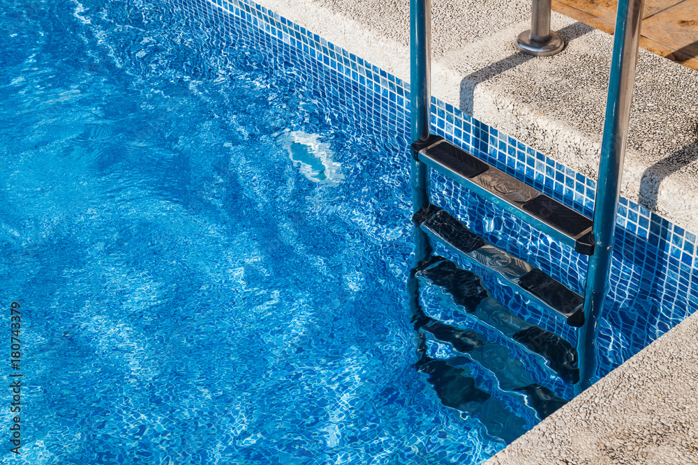 stairs to the pool. Photo of a fragment of the pool with a ladder, clean blue water
