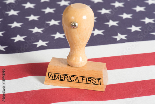 Flagge der USA und ein Stempel mit dem Aufdruck America First photo