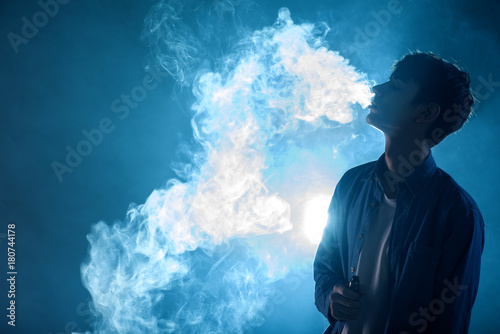man smoking vape and exhales cloud of smoke photo