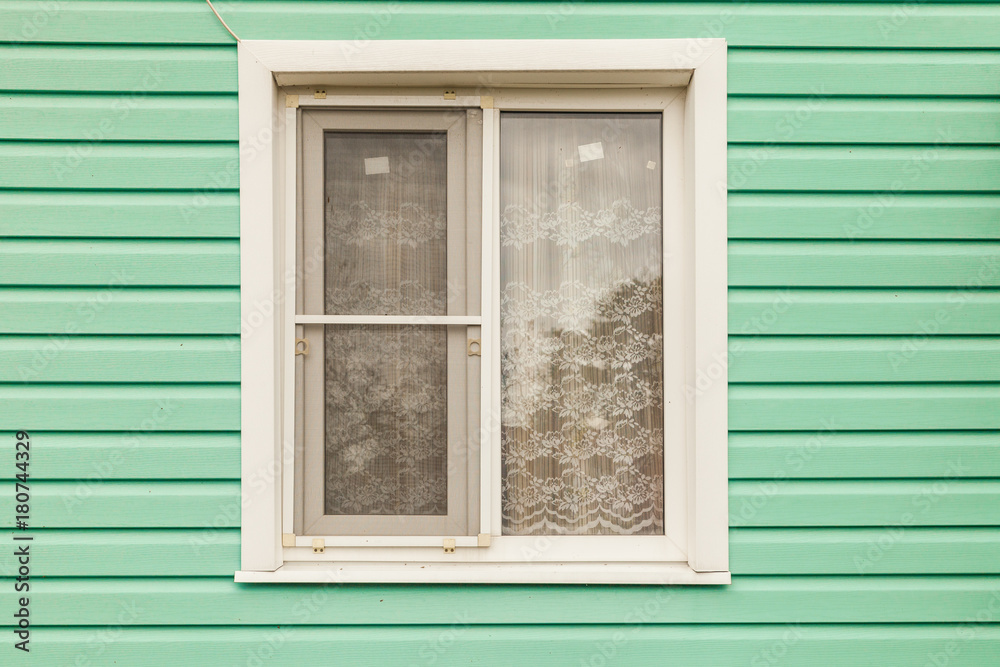 Fototapeta premium Plastic white window on the wall of the green wall house from the siding