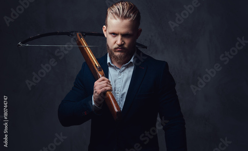 Foto A man dressed in a suit holds crossbow.