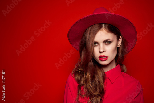beautiful woman in a hat on a red background, lots of free space to copy