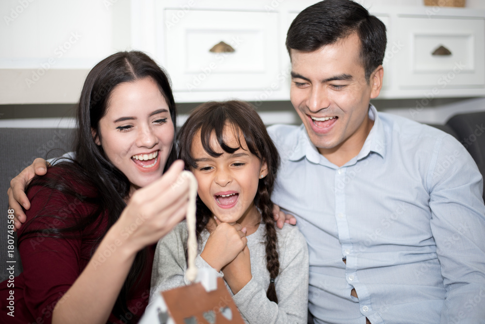 Father and mother surprise their daughter by gift or new toy. Parents and children are happy together in home on sofa. Family and Happiness concept. Father and mother surprise their daughter by gift or new toy. Parents and children are happy together in home on sofa. Family and Happiness concept.