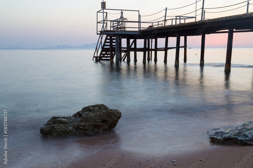 Misty dawn over the sea beach. Stairs to the sea