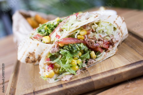 Burrito with grilled chicken and vegetables. Shawarma from juicy beef, lettuce, tomatoes, cucumbers, paprika and onion in pita bread.