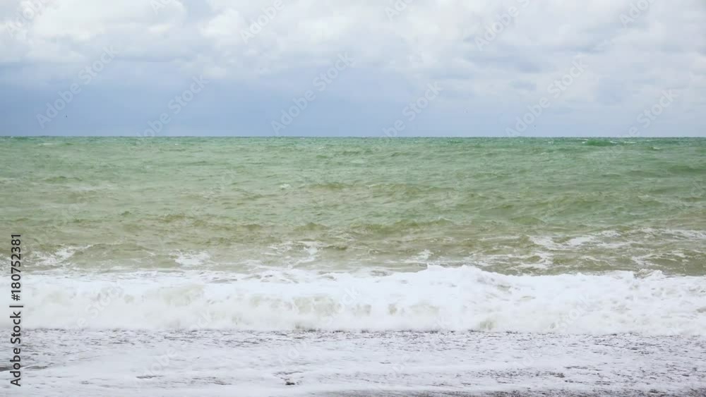 Troubled ocean with waves on a pebble beach Troubled ocean with waves on a pebble beach