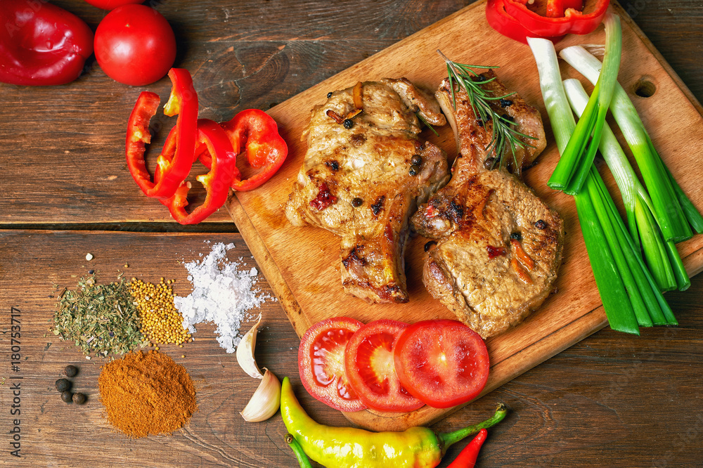 Grilled juicy steak on the bone with vegetables on a dark wooden background. Grilled juicy steak on the bone with vegetables on a dark wooden background.