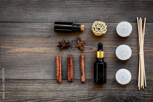 Skin care and relax. Cosmetics and aromatherapy concept. Oil and candles with spices cinnamon on dark wooden background top view copyspace