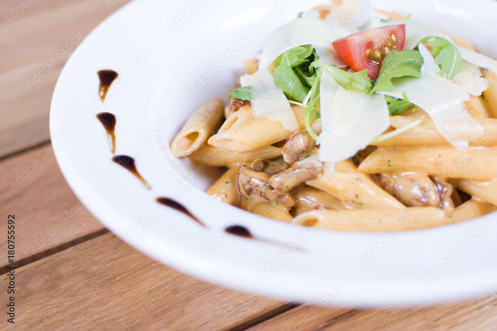 Plate of delicious pasta with savory minced beef and tomato sauce garnished with parmesan cheese and basil.