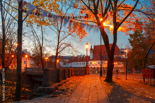 Picturesque Street and autumn park during evening blue hour in Old Town of Vilnius, Lithuania, Baltic states. Saint Anne church on the background.