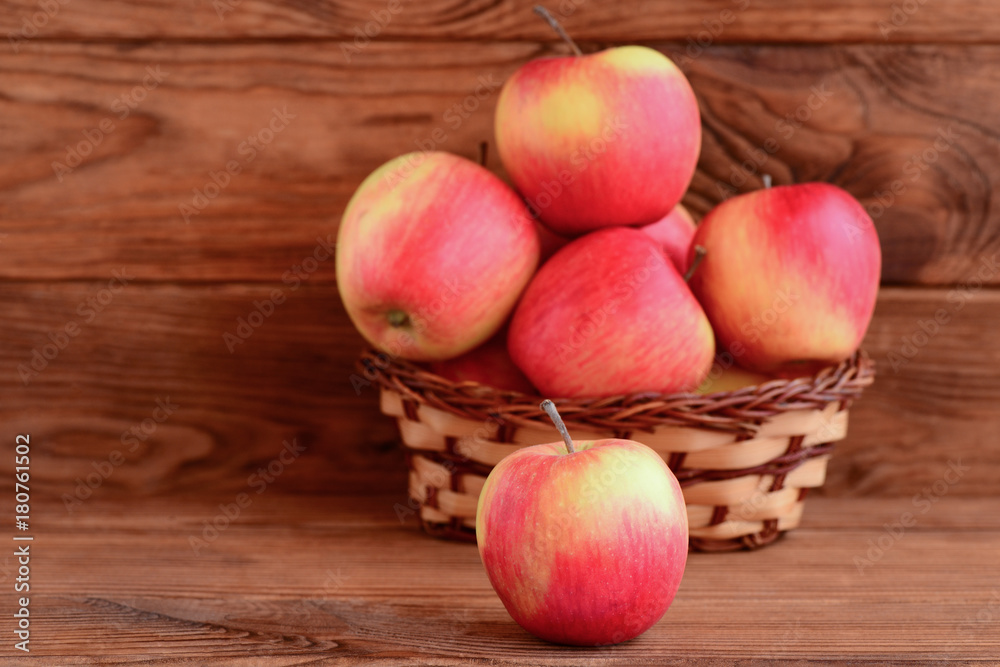 Fresh red apples on a wooden table and in a basket. Brown wooden background with copy space for text. Apples photo. Healthy dessert. Source of pectin and iron Fresh red apples on a wooden table and in a basket. Brown wooden background with copy space for text. Apples photo. Healthy dessert. Source of pectin and iron