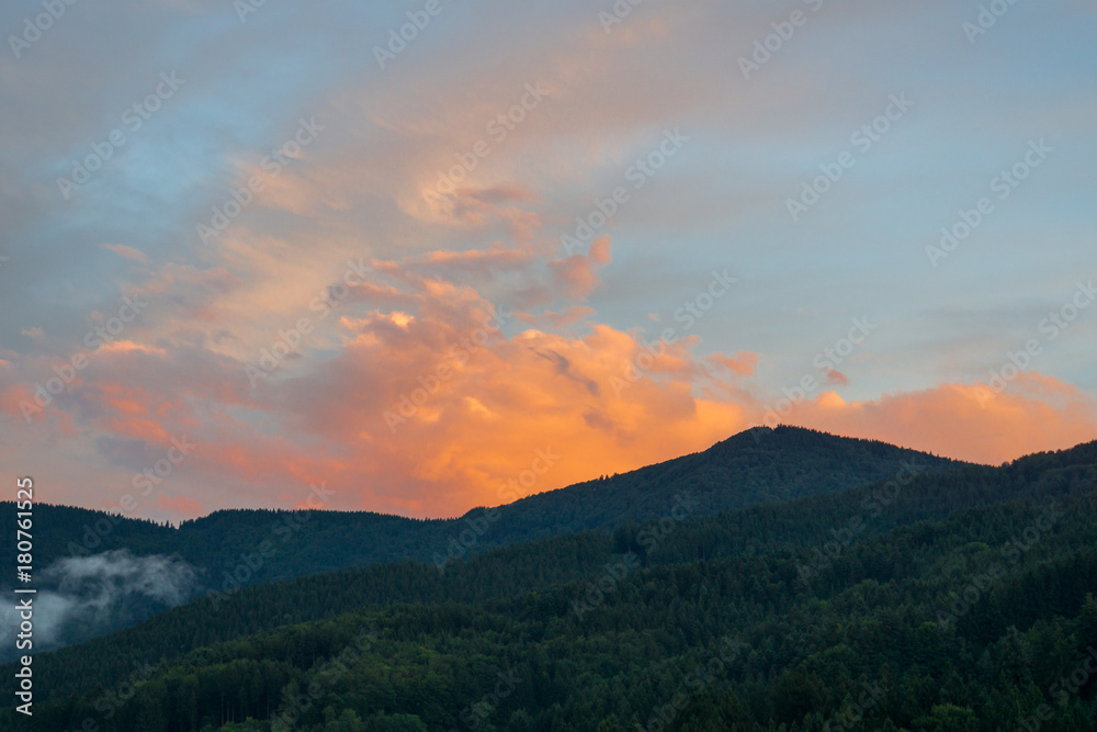 Orange dramatic sky at sunset over forest covered mountains of black forest near Freiburg