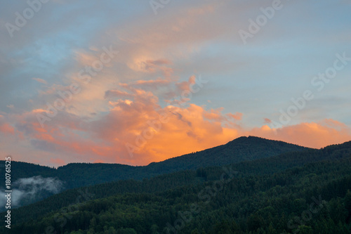 Orange dramatic sky at sunset over forest covered mountains of black forest near Freiburg