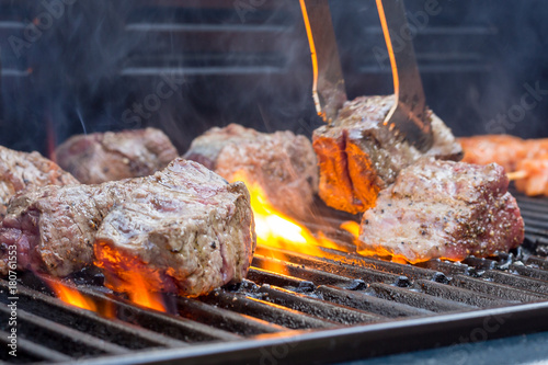 Feuerrote Flamen züngeln um das Grillfleisch auf einem Grillrost, closeup photo