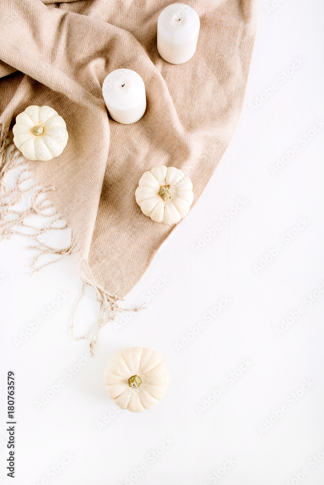White pumpkins and candles on beige plaid. Top view, flat lay autumn or winter composition. White pumpkins and candles on beige plaid. Top view, flat lay autumn or winter composition.