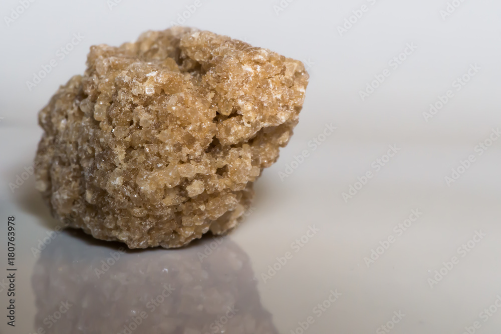 A piece of dark sugar on a white plate A piece of dark sugar on a white plate
