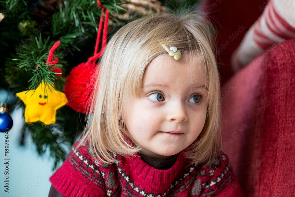 serious sad or thinking young baby caucasian blonde girl portrait at home near christmas tree serious sad or thinking young baby caucasian blonde girl portrait at home near christmas tree