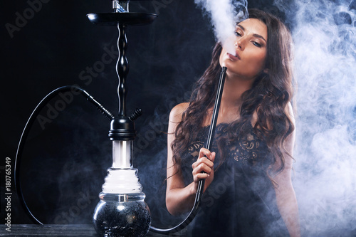 Young, beautiful woman in the night club or bar smoke a hookah or shisha. The pleasure of smoking. Sexy smoke.