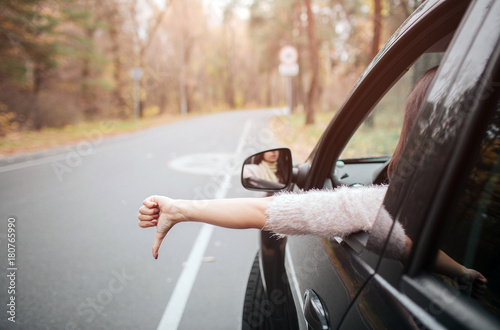 Female traveler on the road holding thumb down. Fall vacation, holidays, travel, road trip and people concept photo