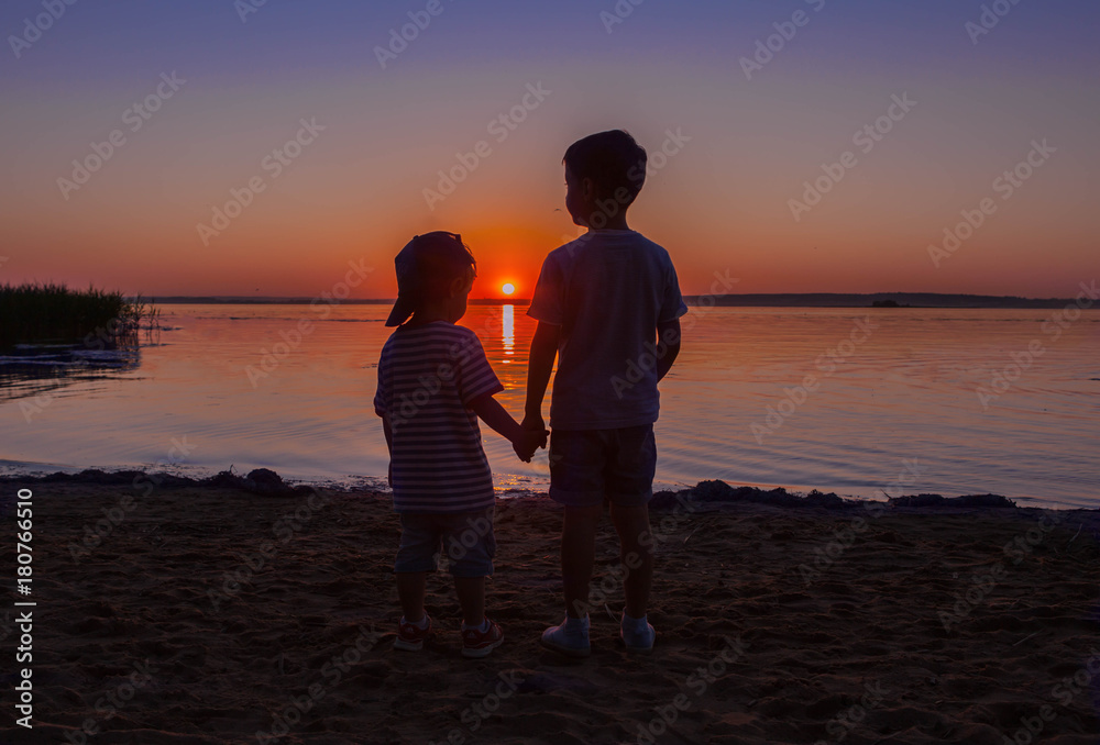 Two boys brothers watch the pretty sunset.
