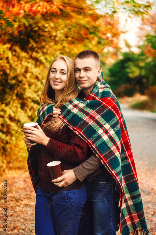 Fototapeta premium the relationship between a guy and a girl. a hot drink in the hands. a blanket warms two. smile on his face. sunny day