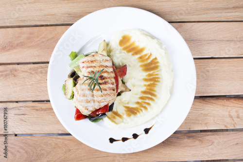 Grill chicken breast. Grilled vegetables with chicken breast. Grilled chicken with vegetables on oak table.