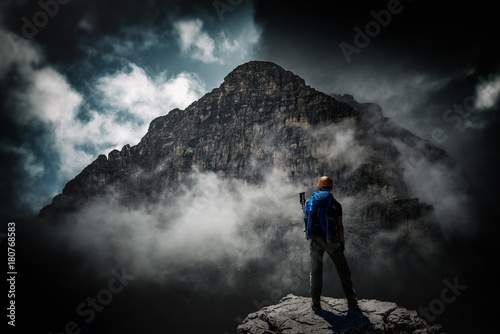 Valokuva Mountaineer standing below looming dark mountain