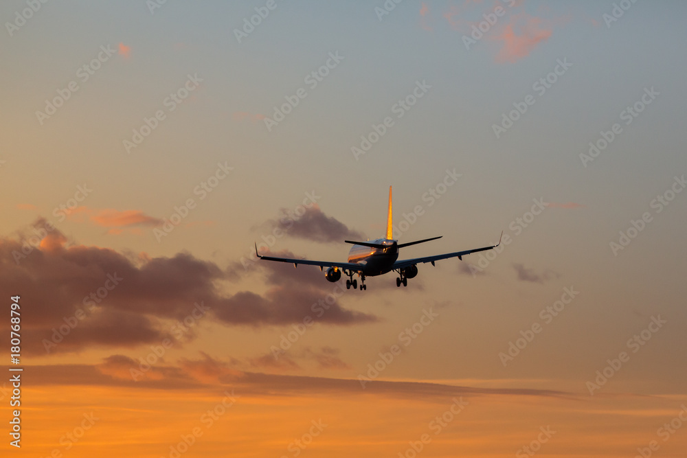 Airplane is landing at airport during a wonderful sunset sky background / orange sky