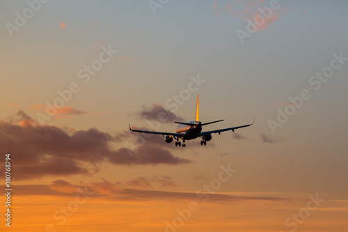 Airplane is landing at airport during a wonderful sunset sky background   orange sky
