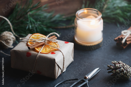 View of the gift box in a kraft paper decorated dried orange slices and cinnamon sticks. The cincept of preparation of gifts for the New Year and Christmas. photo