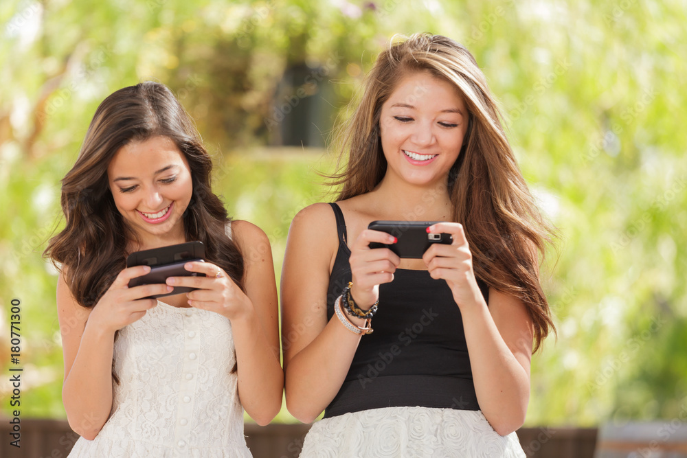 Two Expressive Mixed Race Girlfriends Using Their Smart Cell Phones Outdoors Two Expressive Mixed Race Girlfriends Using Their Smart Cell Phones Outdoors