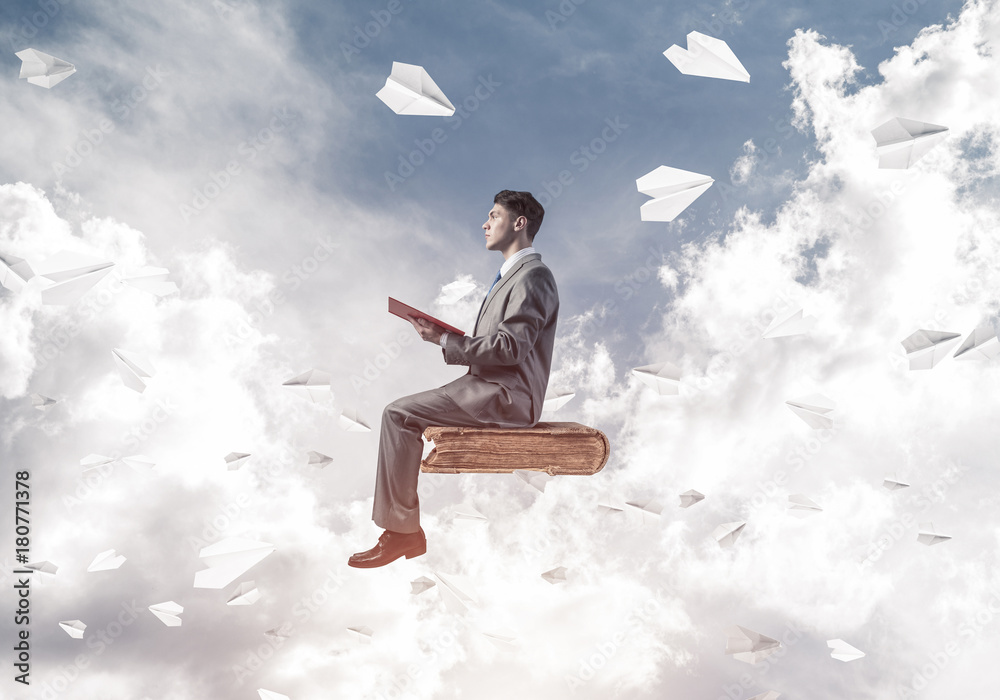 Businessman or student reading book and paper planes flying arou Businessman or student reading book and paper planes flying arou