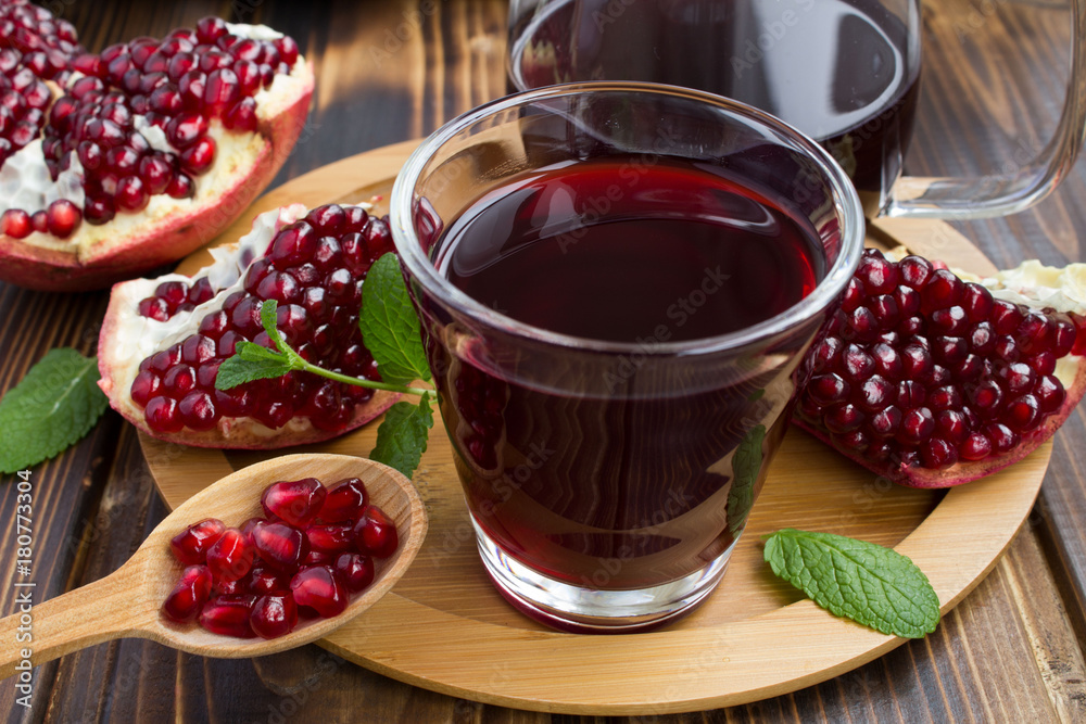 Pomegranate juice in the glass on the round cutting board Pomegranate juice in the glass on the round cutting board