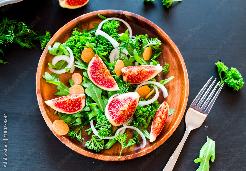 Autumn salad of arugula, figs in a brown earthenware plate on a dark background. top view Autumn salad of arugula, figs in a brown earthenware plate on a dark background. top view