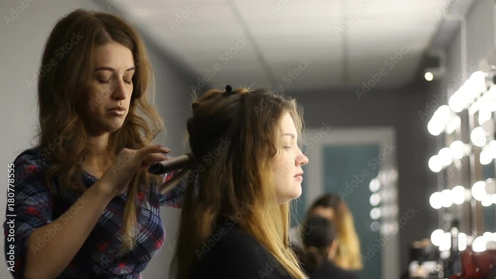 Beautiful hairstylist curling hair woman client in hairdressing beauty salon Beautiful hairstylist curling hair woman client in hairdressing beauty salon