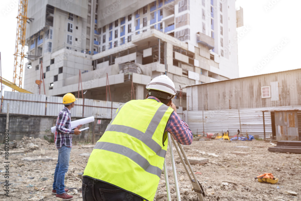 Asian civil engineer checking work for control and management in the construction site or building site of high rise building.