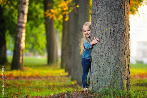 Little girl hugging a tree and smile in park photo