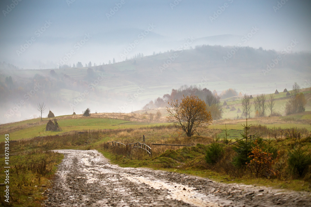 Muddy ground and country road after rain in mountains.
