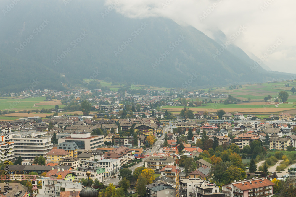 Mesmerising top view on the autumnal city Brunico surrounded by mountains from the tower of Bruneck castle in Alto Adige, Italy, Europe